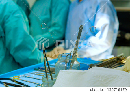 Surgeons prep for surgery with key tools on tray team members focused an operating room background. Surgeons prep for surgery with key tools on tray team members focused an operating room background. 136716179
