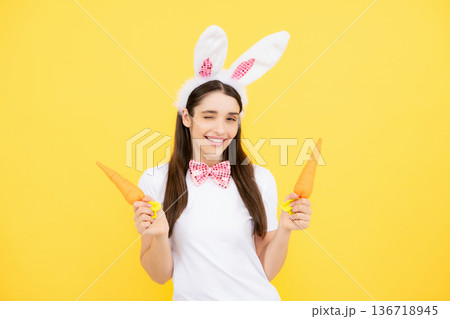 Funny woman with bunny ears celebrate easter on yellow studio background. Bunny girl face. Woman in easter rabbit mask. Funny woman with bunny ears celebrate easter on yellow studio background. Bunny girl face. Woman in easter rabbit mask. 136718945