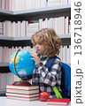 Pupil looking at globe in library at the elementary school. Back to school. Portrait of cute child school boy. Clever kid with school supplies. 136718946