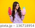 Teenager child girl with bottle shampoo conditioners or shower gel. Kids hair care. Hair cosmetic product, shampoo bottle. Happy teenager, positive and smiling emotions of teen girl. 136718954