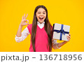 Teenager girl hold gift box. Child holding gift box in Christmas or birthday. Girl with giftbox for mothers day. Portrait of a little girl with a gift on isolated background. Birthday, presents gift. 136718956