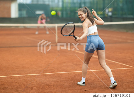 Young woman making serve while playing tennis Young woman making serve while playing tennis 136719101