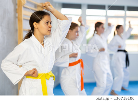 Young female students repeat position and perform sequence of punches and painful techniques kata Young female students repeat position and perform sequence of punches and painful techniques kata 136719106