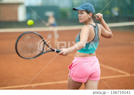 Young woman making serve while playing tennis 136719141