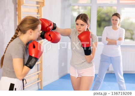 Women in boxing gloves punch deliver blow each other during training sparring session. Women in boxing gloves punch deliver blow each other during training sparring session. 136719209