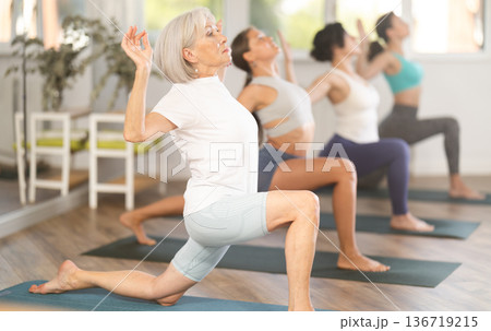 Elderly woman doing pilates in group in studio Elderly woman doing pilates in group in studio 136719215