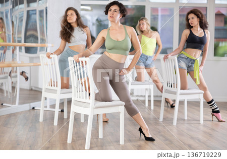Female dancer in high heels practicing lap dance on chair in studio Female dancer in high heels practicing lap dance on chair in studio 136719229