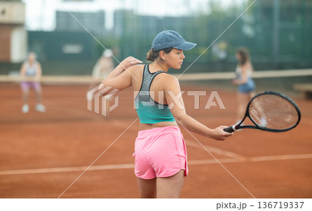 Two young women playing tennis against elderly women 136719337