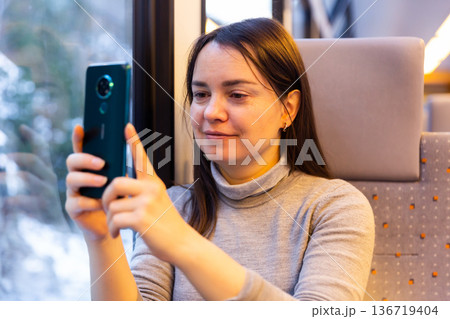 Woman photographing with her smartphone while traveling by train 136719404