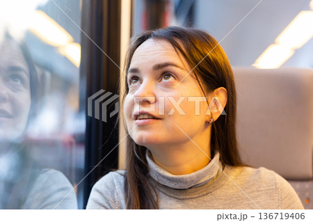 Woman traveler sitting inside train and looking out window Woman traveler sitting inside train and looking out window 136719406