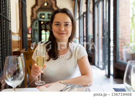 Dreamy woman with glass of wine at table in restaurant 136719408