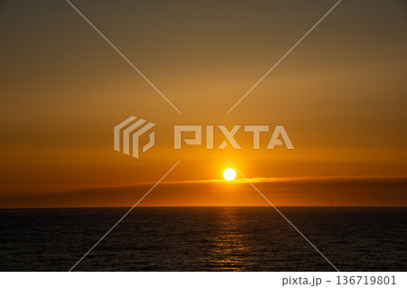 オレンジ色に反射する雲が美しい海の夕暮れ 136719801