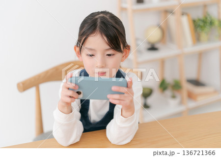 スマホを見る小学生の女の子 136721366