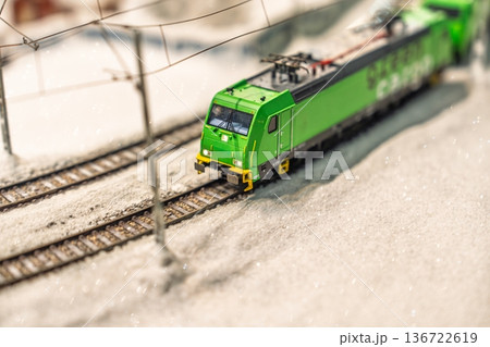 Miniature Train on Tracks in Snow Captivating Winter Scene with a Green Locomotive 136722619