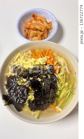 Janchi Guksu, a light and savory Korean noodle dish served in a clear broth, topped with vegetables, egg strips, and seaweed. A simple yet flavorful meal often enjoyed on special occasions. 136722774
