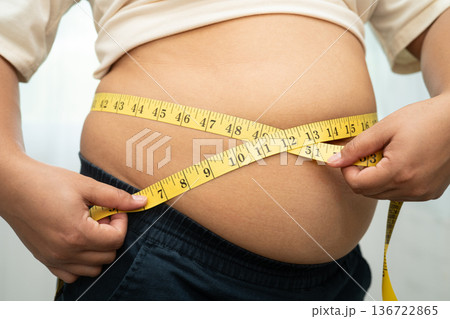 Asian woman with fat belly big size overweight and obesity with measure tape. 136722865