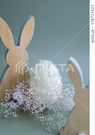 Creative Easter egg shape made of white lilac spring petals flowers. Responsible holidays decoration wooden rabbit bunny decor. Minimal holiday concept still life. Copy space Creative Easter egg shape made of white lilac spring petals flowers. Responsible holidays decoration wooden rabbit bunny decor. Minimal holiday concept still life. Copy space 136723421