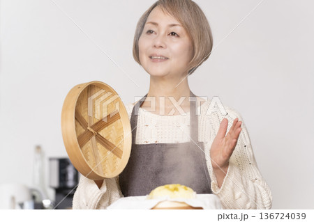 キッチンでさつま芋の蒸しパンをせいろで蒸して作るシニア女性 キッチンでさつま芋の蒸しパンをせいろで蒸して作るシニア女性 136724039