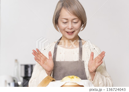 キッチンでさつま芋の蒸しパンをせいろで蒸して作るシニア女性 キッチンでさつま芋の蒸しパンをせいろで蒸して作るシニア女性 136724043