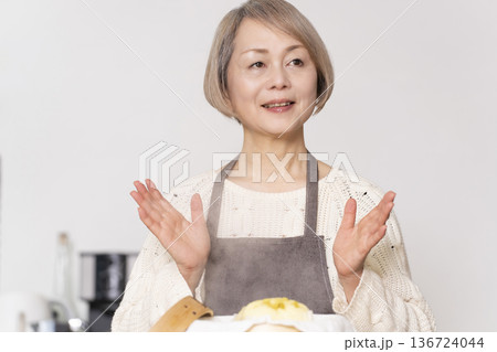 キッチンでさつま芋の蒸しパンをせいろで蒸して作るシニア女性 136724044