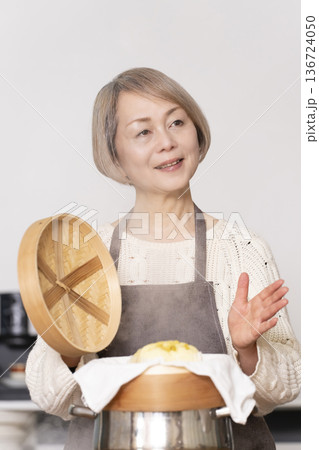 キッチンでさつま芋の蒸しパンをせいろで蒸して作るシニア女性 キッチンでさつま芋の蒸しパンをせいろで蒸して作るシニア女性 136724050