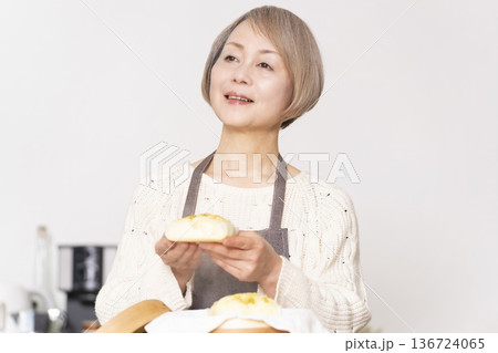 キッチンでさつま芋の蒸しパンをせいろで蒸して作るシニア女性 キッチンでさつま芋の蒸しパンをせいろで蒸して作るシニア女性 136724065