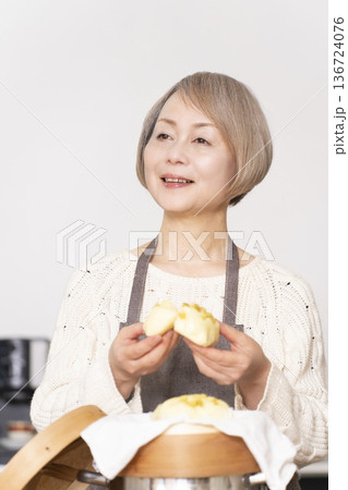 キッチンでさつま芋の蒸しパンをせいろで蒸して作るシニア女性 キッチンでさつま芋の蒸しパンをせいろで蒸して作るシニア女性 136724076