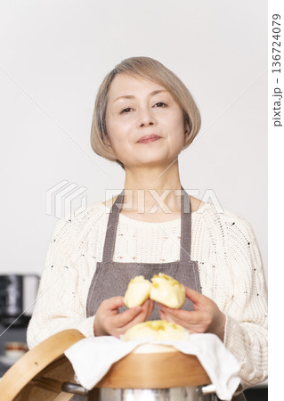 キッチンでさつま芋の蒸しパンをせいろで蒸して作るシニア女性 キッチンでさつま芋の蒸しパンをせいろで蒸して作るシニア女性 136724079