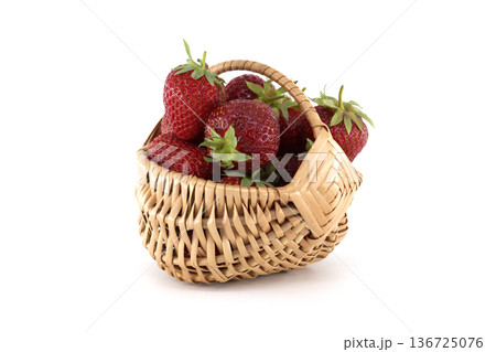 Wicker basket overflowing with fresh strawberries on white background 136725076
