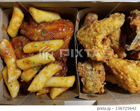 Golden crispy fried chicken served alongside bright yellow pickled radish slices, showing crunchy texture, juicy meat, and vibrant contrast of colors on a clean plate in close-up detail 136725642