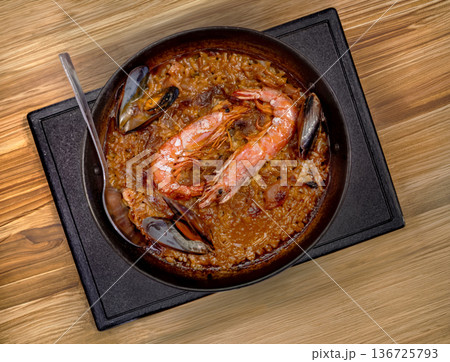 Traditional Spanish seafood paella with large prawns and mussels served in a rustic iron pan on a wooden table. Authentic Mediterranean gastronomy and gourmet dining concept Traditional Spanish seafood paella with large prawns and mussels served in a rustic iron pan on a wooden table. Authentic Mediterranean gastronomy and gourmet dining concept 136725793
