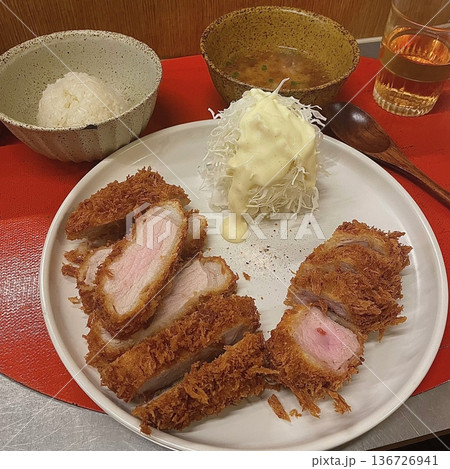 Crispy tonkatsu, a Japanese-style breaded and deep-fried pork cutlet, served with shredded cabbage and drizzled with savory sauce. A delightful balance of crunchy texture and juicy meat. Crispy tonkatsu, a Japanese-style breaded and deep-fried pork cutlet, served with shredded cabbage and drizzled with savory sauce. A delightful balance of crunchy texture and juicy meat. 136726941