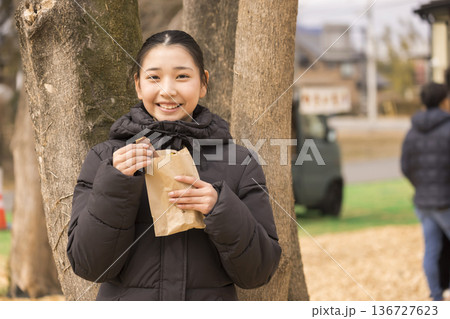 焼き芋を袋から取り出す笑顔の女の子 136727623