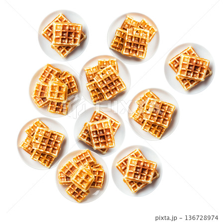 Multiple plates of golden waffles with creamy topping isolated on white background, concept of delicious breakfast food Multiple plates of golden waffles with creamy topping isolated on white background, concept of delicious breakfast food 136728974