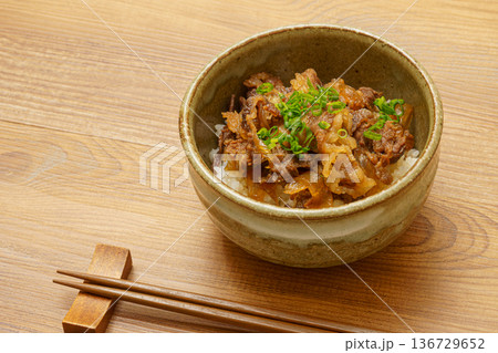 木目調テーブルに置かれた牛丼と箸の和食イメージ 136729652