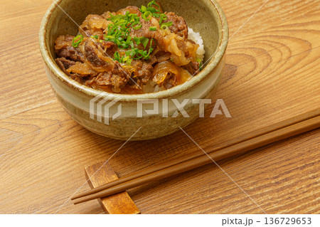 木目調テーブルに置かれた牛丼と箸の和食イメージ 136729653