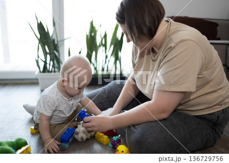 Caregiver Teaches Child Through Play. Mother Patiently Assists Child Exploring Shapes Caregiver Teaches Child Through Play. Mother Patiently Assists Child Exploring Shapes 136729756