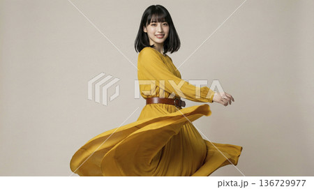 黄色のロングドレスをなびかせて回転する笑顔の日本人女性 136729977