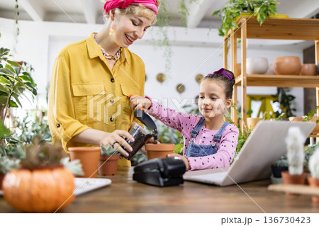 A young girl and her mother enjoy a fun gardening activity, learning about plants and nature together A young girl and her mother enjoy a fun gardening activity, learning about plants and nature together 136730423