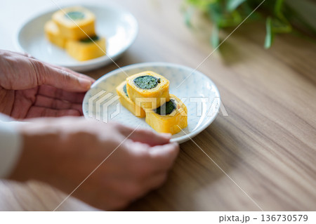 ほうれん草入り卵焼きを取り分ける手元 136730579