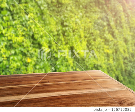 Simple natural wood table with a blurred green tree background. 136733083
