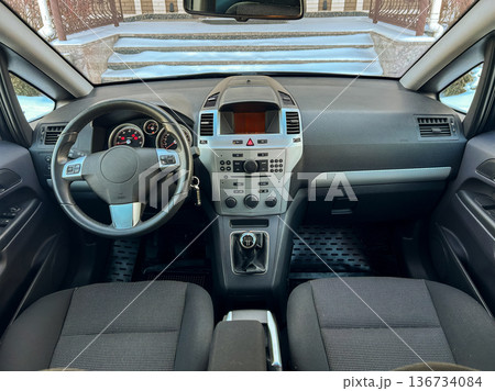 Interior view of a compact car parked outside a building on a snowy day with a focus on the dashboard and front seats Interior view of a compact car parked outside a building on a snowy day with a focus on the dashboard and front seats 136734084