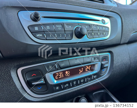 Control panel in a car showing radio settings and climate control options during daylight hours 136734152