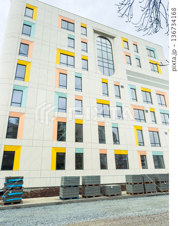 New building under construction with colorful panels and stacks of materials on the ground near the site in the city New building under construction with colorful panels and stacks of materials on the ground near the site in the city 136734168