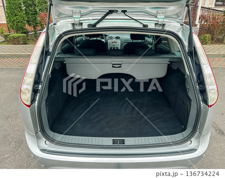 Cargo space in a silver hatchback parked in a driveway with clean surfaces and a well-kept garden in the background during daylight hours 136734224