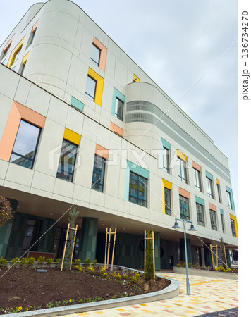 New building in urban area shows colorful facade and landscaping next to sidewalk in daytime during overcast weather New building in urban area shows colorful facade and landscaping next to sidewalk in daytime during overcast weather 136734270