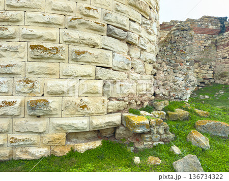 Historic stone wall stands in ruins with moss and grass at the site in a rural area during the daytime Historic stone wall stands in ruins with moss and grass at the site in a rural area during the daytime 136734322
