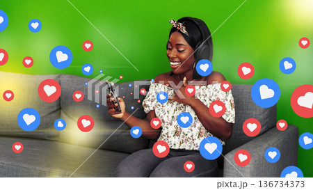 Podcast host interacts with audience using phone and headphones at home in a green background Podcast host interacts with audience using phone and headphones at home in a green background 136734373