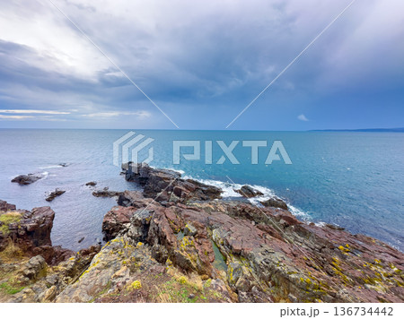 Sky over rocky coastline and ocean with waves on a cloudy day near the shore in a seaside area 136734442