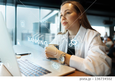 Businesswoman working on banking invoice payment in a modern office setting 136734502